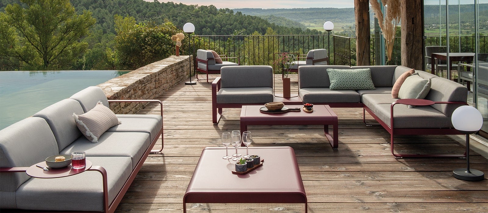 Fermob Bellevie Bank in Kirschschwarz mit Mooon Leuchten auf einer eleganten Abendterrasse