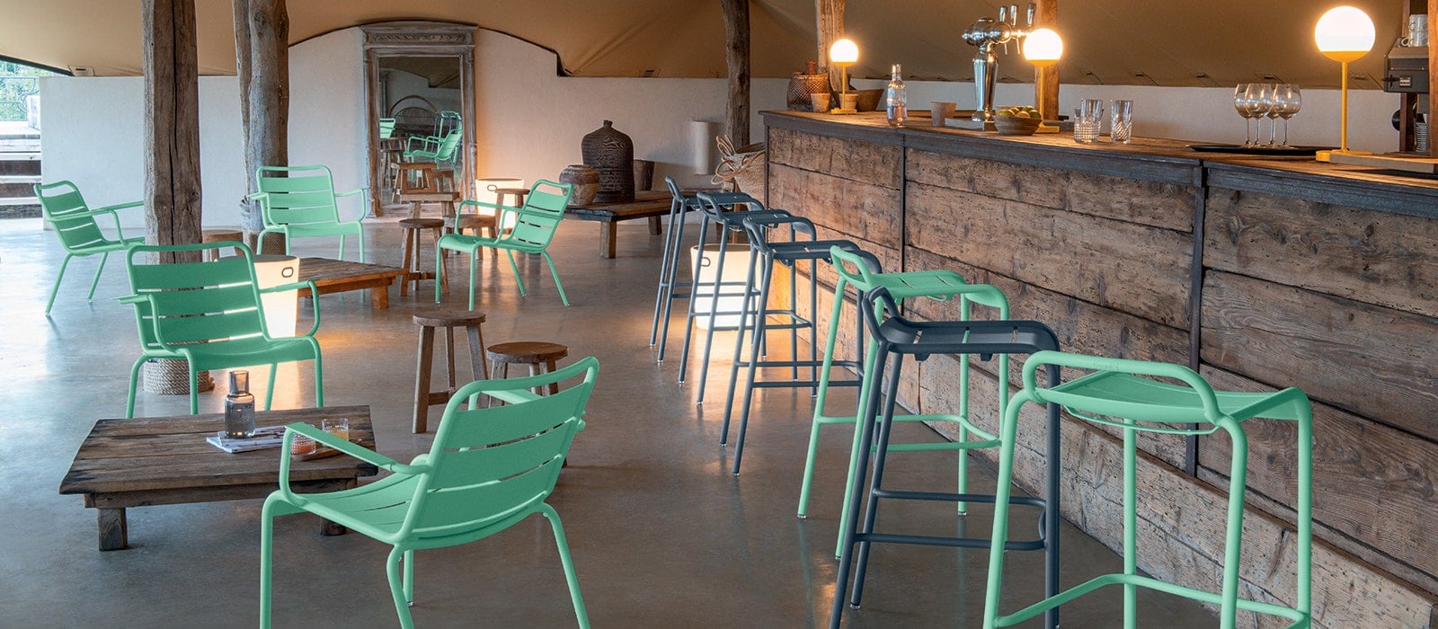 Fermob Luxembourg Stühle in Opalgrün mit Mooon Leuchten in einem mediterranen Garten